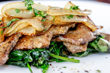 Grilled Liver with Onions closeup in the bowl served with bread on the table.