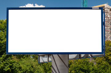 Blank white billboard for advertisement near construction site of modern apartement building among trees