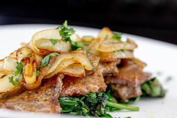 Grilled Liver with Onions closeup in the bowl served with bread on the table.
