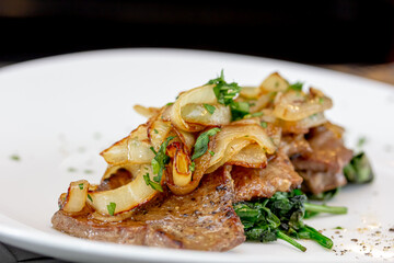 Grilled Liver with Onions closeup in the bowl served with bread on the table.