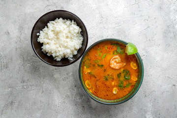 Tom Yam soup with shrimps and cilanto with rice on grey table top view