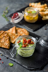 Avocado mousse with dried tomatoes with fried bread on dark stone plate vertical