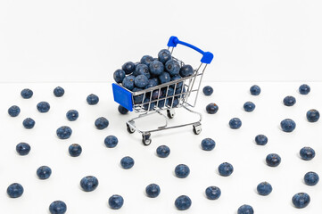 Blueberries in shopping cart and scattered berries isolated on white background. Shopping for...
