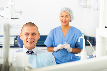 Obraz premium Closeup of happy man sitting in dental chair after teeth cure at stomatology clinic office