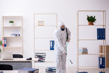 Young male contractor disinfecting office during pandemic