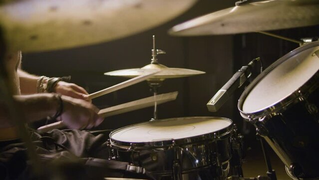 Young male drummer playing drums at music studio while rehearsing alone. Musician performing on percussion instruments. High angle shot. Music, musical instruments concept