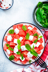 Refreshing summer juicy Watermelon salad with feta cheese and fresh mint, gray table background, top view, copy space