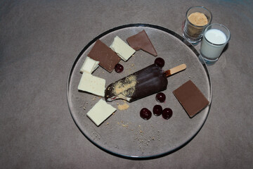 glass plate with chocolate ice cream cherries and small glasses of milk and plasma, creative sweet summer meal, idyllic picture