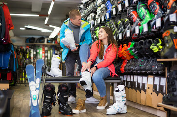 Fototapeta na wymiar Customer male and female are trying on boots for skiing in a sportswear store