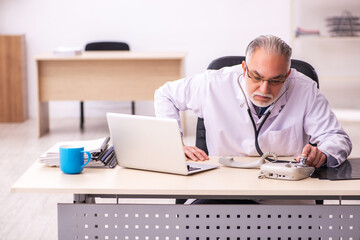 Aged male doctor working in the clinic