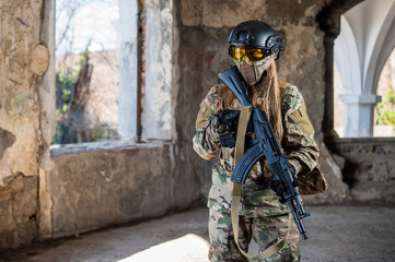 Portrait of a woman in a helmet and goggles with a machine gun in her hands. A female soldier in a...