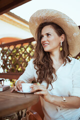 smiling trendy woman in shirt sitting at table