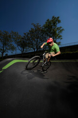 rider with a dirt bike training on a pump track. the rider is riding up a bank.