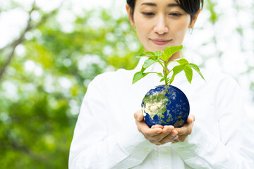 地球の模様の鉢植えを持つ女性　環境イメージ　SDGs　サステナブル