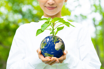 Asian woman holding a flowerpot with a pattern of the earth. Environment concept. Sustainable...