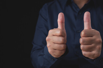 Person that wear dark blue shirt shows thumbs up sign. Salaryman or business man. Like or good concept. Close up shot with copy space.