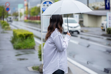 傘をさしてバス停で待つ女性　bus station