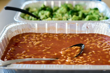 Two large containers with boiled beans and steamed vegetables prepared by volunteers for refugees in camp or people in need