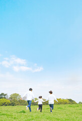 青空の草原を走る家族　環境　子育て