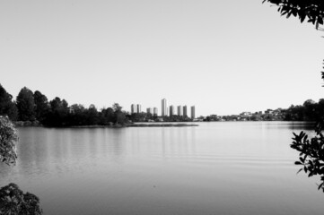 Obraz premium Black and white photograph of a lake with the view of the big city