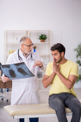 Fototapeta premium Young male doctor visiting old male doctor radiologist