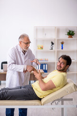 Fototapeta premium Young male patient visiting old male doctor chiropractor