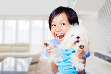 Excited little girl play with a Maltese dog at home