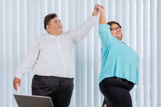 Happy fat business couple dancing in office