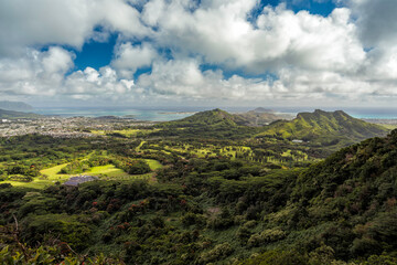 High angle view from Pali Lookout on the island of Oahu, Hawaii. Scenic view of the lush forest, ocean and white puffy clouds on blue sky
