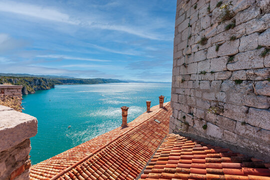 View of the coast from Duino Castle on a cliff above the Gulf of Trieste (Adriatic Sea), Italy. Medieval tiled roof of the Duino fortress.