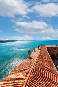 View of the coast from Duino Castle on a cliff above the Gulf of Trieste (Adriatic Sea), Italy. Medieval tiled roof of the Duino fortress.