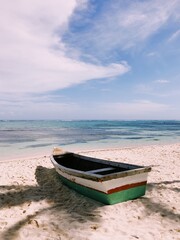 Fototapeta na wymiar Old wooden boat on the beach with white sand and calm clean ocean view