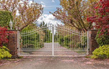 Iron front gate of a luxury home. Wrought iron white gate and brick pillar