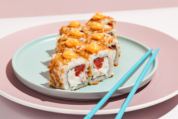 Alternative maki roll with chicken on coloured background. Sushi roll with chicken, cheese and tomato inside, bread crumbs outside. Maki sushi in minimal style. Japanese menu concept.