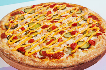 Italian pizza with chicken and pickled cucumber on coloured background. Cheese pizza with chicken in minimal style on purple and blue colours. American pizza delivery concept with color backdrop
