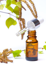Birch essential oil in a brown bottle with a pipette, birch branches with earrings