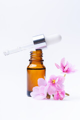 Brown bottle with essential oil and pink violet flower on a white background