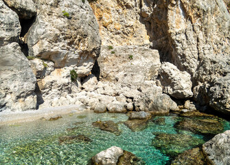 Transparent, cool sea under cliffs and clear blue sky. Summer in Greece.