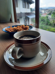A cup of black coffee and crispy mushroom snacks