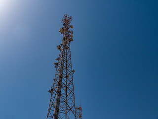 Relay tower with many antennas against the blue sky.