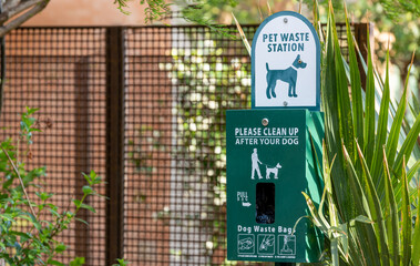 Pet waste station in park with plastic bags and instructions for use. Public dog feces disposal...