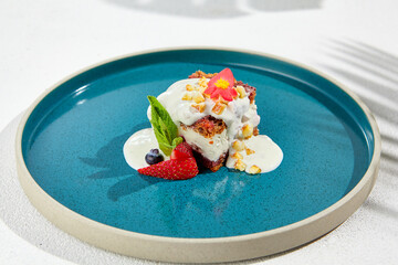 Carrot cake with cream cheese and berries on ceramic plate. Elegant dessert - carrot pie on white background with shadows of leaves. Portion cake on modern plate in minimal style.