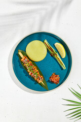 Squid yakitori in ceramic dish on white background. Japanese skewered squid with wasabi sauce. Grilled kalmar on bamboo skewer in asian style. Food menu for izakaya. Summer pan asian menu. © Ryzhkov