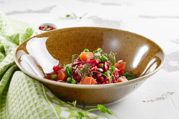 Traditional Russian salad - vinaigrette from boiled vegetables, cabbage and green pease. Vinaigrette salad with salmon in rustic style. Vegetarian dish in bowl on stone background. Russian food.