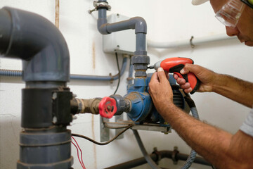Technician repairing with a drill the irrigation system of an agricultural production.