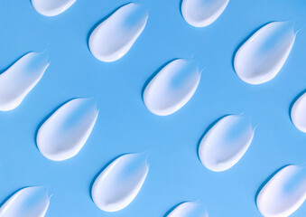 Fototapeta na wymiar pattern of smears of white cream on a light blue background 