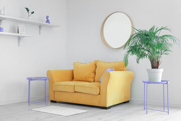 Interior of light living room with yellow sofa, mirror and houseplant