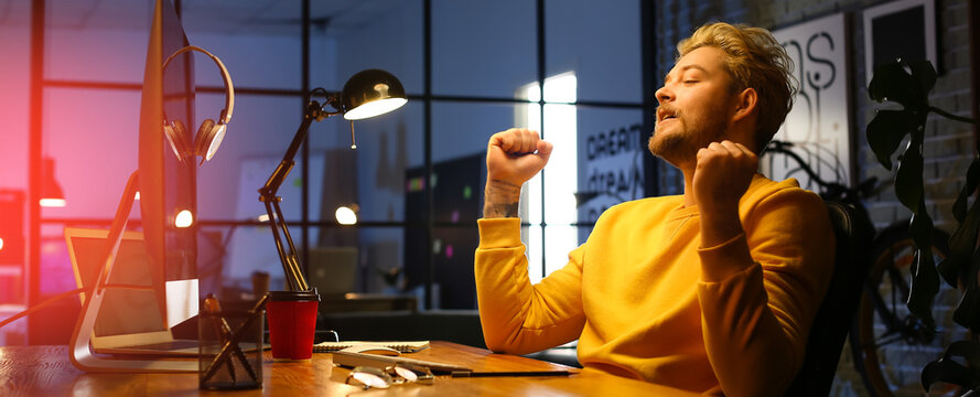 Happy programmer working in office at night