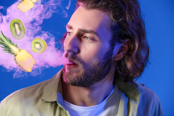Young man smoking electronic cigarette with fruit flavor on blue background