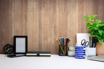 Stylish workplace with flower pot, coffee cup and stationery on white table. Home office. Copy space for advertise text, information content.